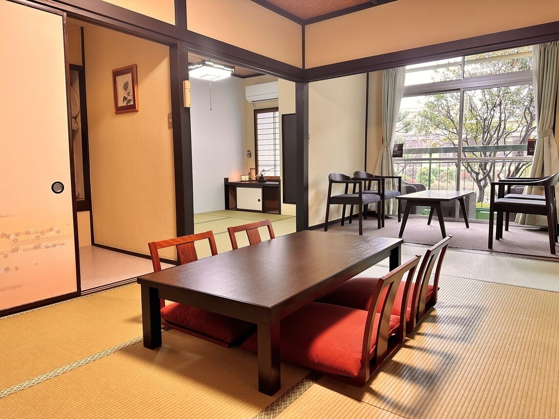 A traditional Japanese-style room with tatami flooring, a wooden table, and chairs.