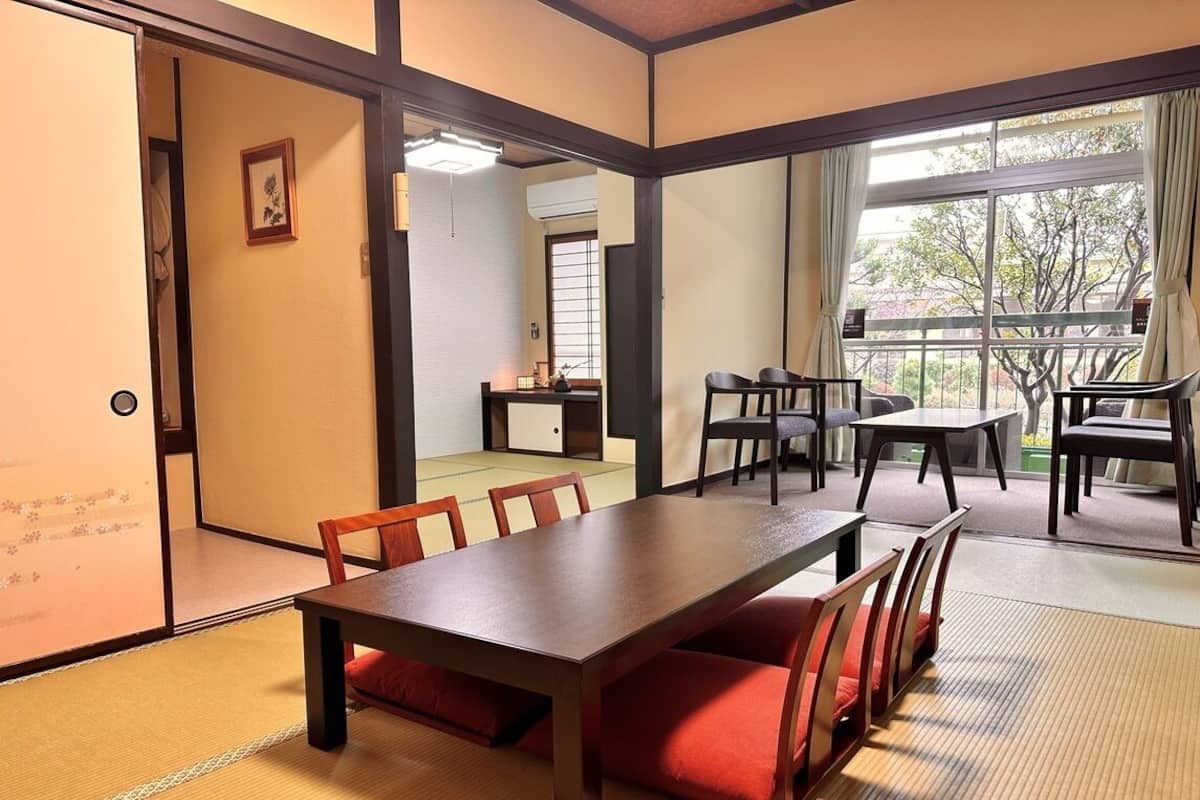 A traditional Japanese-style room with tatami flooring, a wooden table, and chairs.