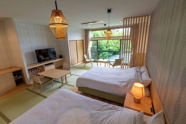 A hotel room with two beds, a desk with a TV, a chair, and a view of greenery through the window. - Koubounoyu Honten (Izunokuni)