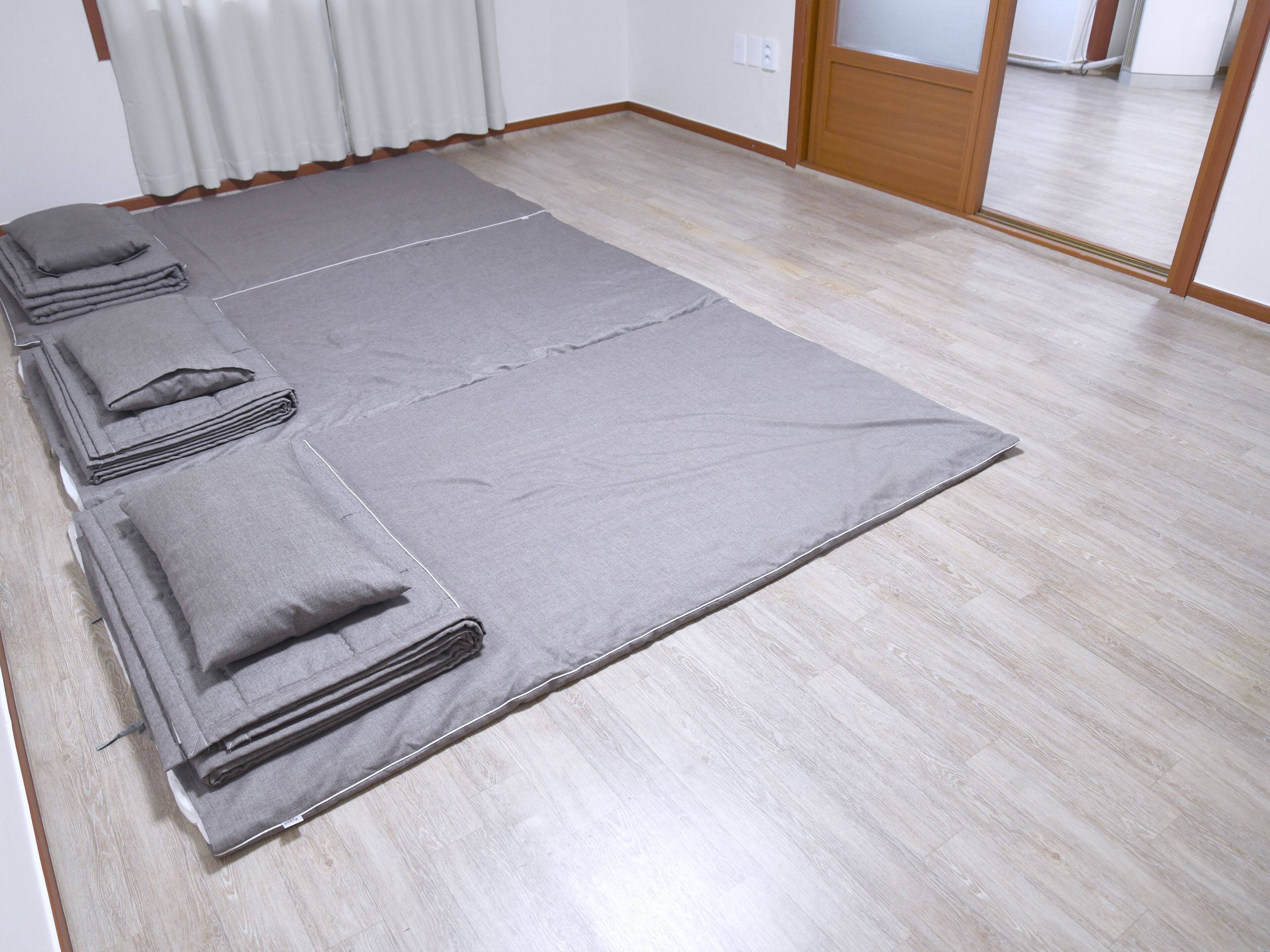 Una stanza con un grande tappeto grigio sul pavimento, un termosifone e una porta in legno.