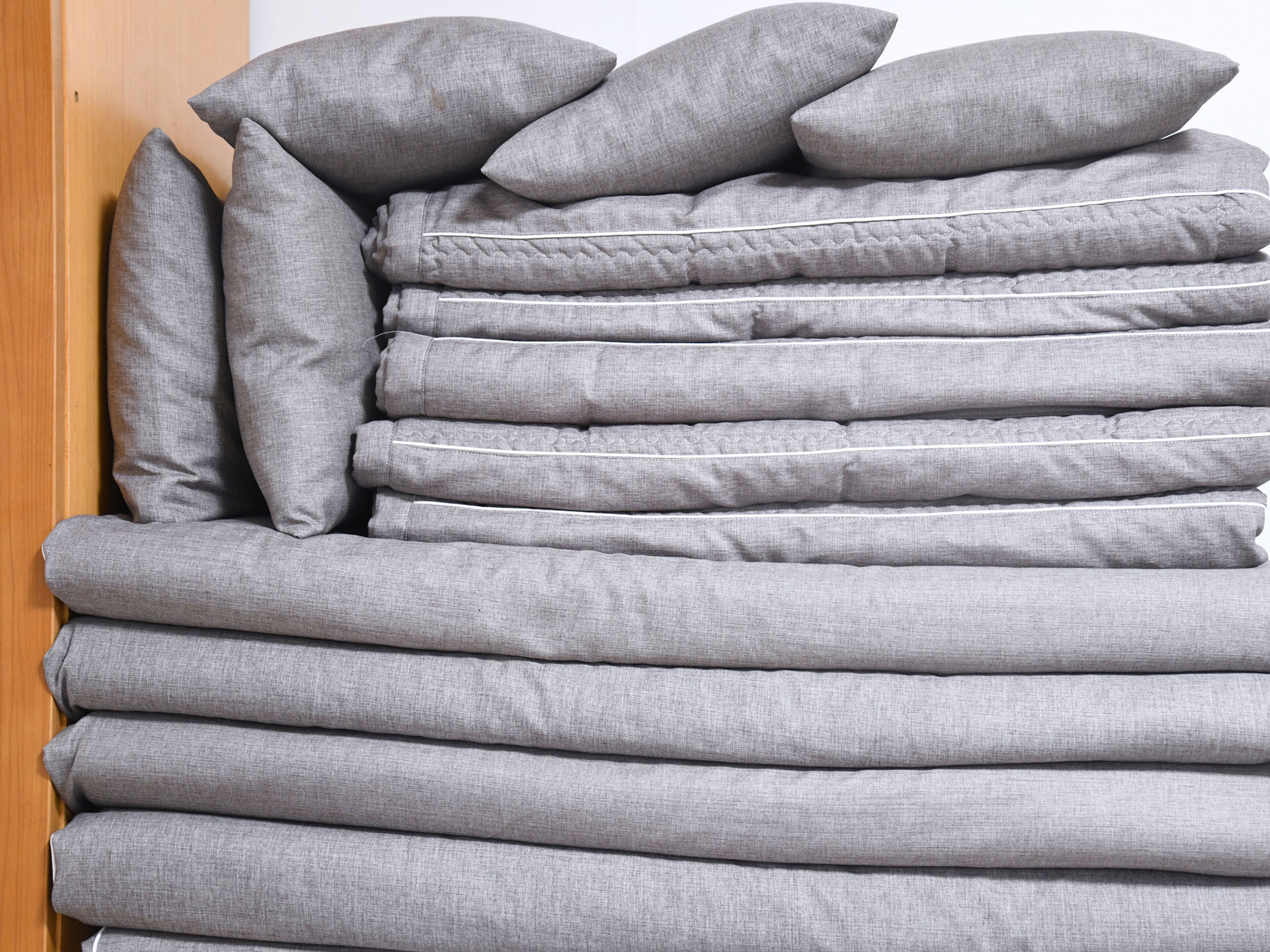 A stack of grey pillows against a wooden door.