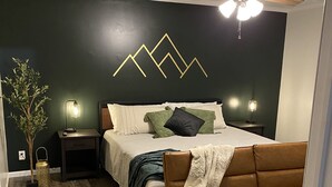 Ein Schlafzimmer mit einem Bett, einem Nachttisch, einer Lampe, einem Deckenventilator und einer Wandleuchte.