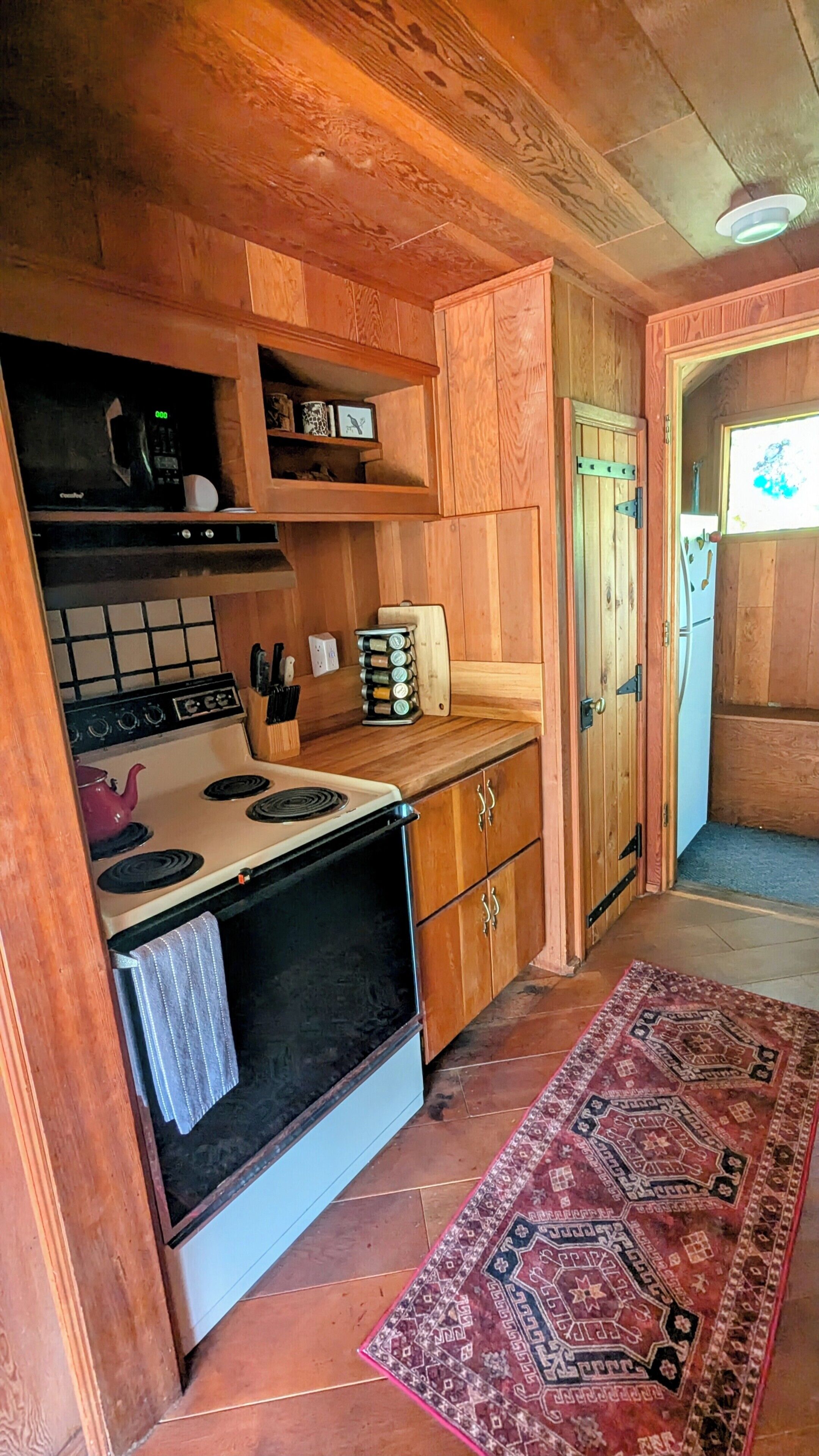 Una cocina compacta con armarios de madera, una estufa y una pequeña encimera.