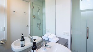 Un baño moderno con dos lavamanos, cabina de ducha de vidrio y un perchero para toallas.