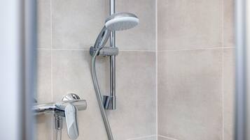 A modern shower with a handheld showerhead and a wall-mounted control valve.