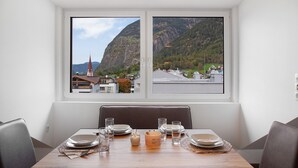 Mesa para cuatro personas dispuesta con vista a un paisaje montañoso a través de una ventana.