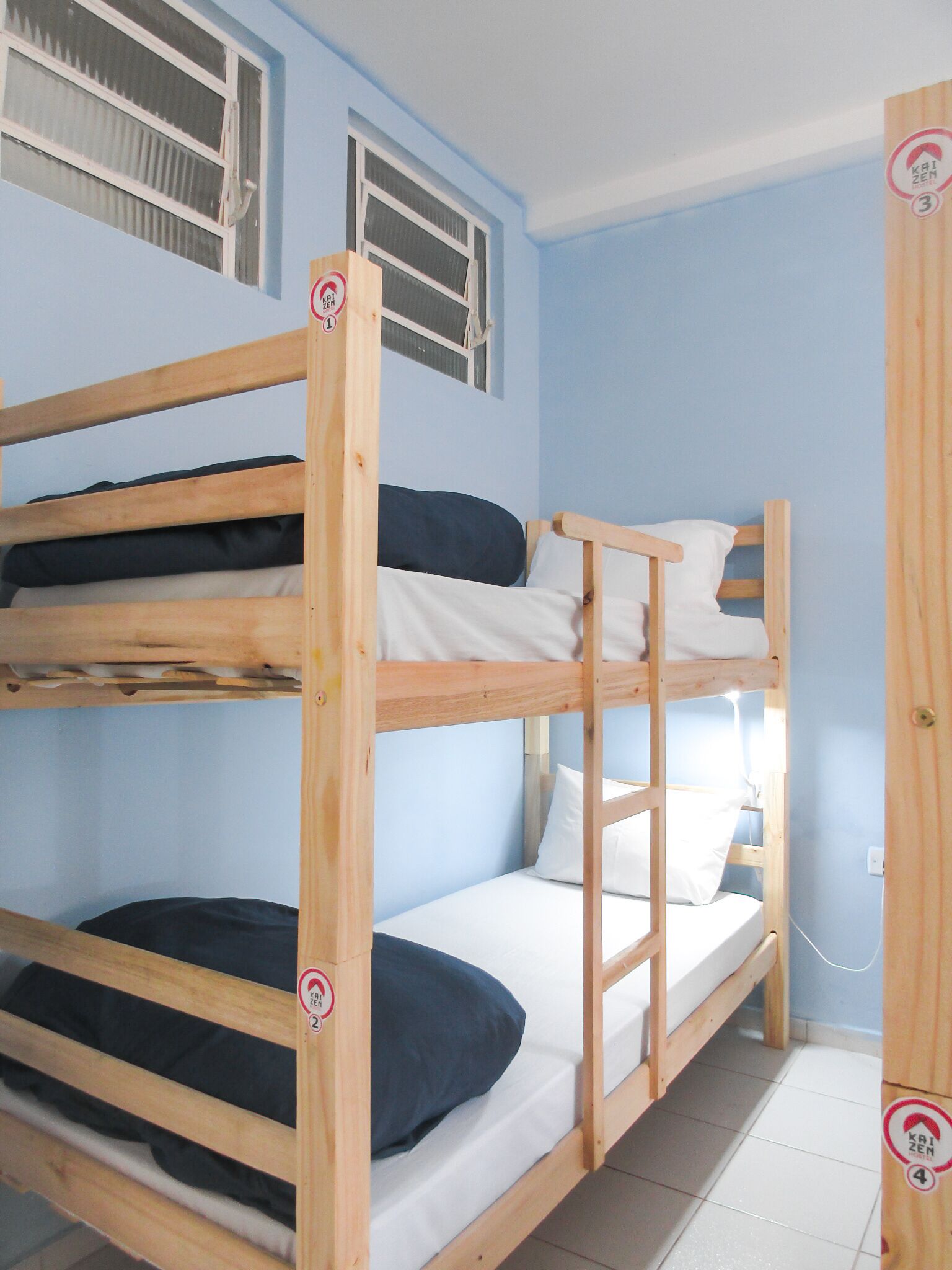 Une chambre avec un lit superposé, comportant deux lits, chacun avec un oreiller et une couverture.