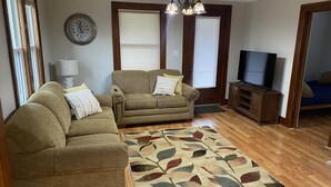 A living room with a sofa, a coffee table, a TV stand, and a patterned rug. - Duplex Apartment Walking Distance to Downtown Wyandotte  (Wyandotte)