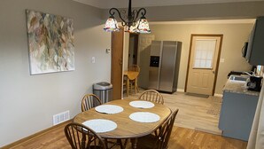 A dining area with a wooden table and chairs, a chandelier, and a kitchen in the background. - Duplex Apartment Walking Distance to Downtown Wyandotte  (Wyandotte)
