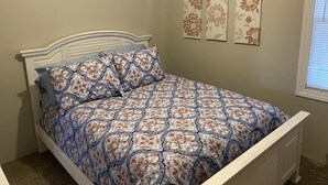 A bed with a patterned bedspread, a white headboard, and three wall-mounted floral decorations. - Duplex Apartment Walking Distance to Downtown Wyandotte  (Wyandotte)