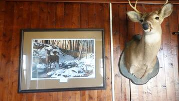 A framed photograph of a deer in a snowy landscape, mounted on a wooden wall next to a deer head.