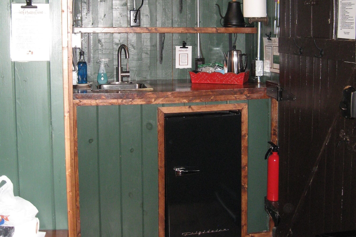 A compact kitchen with a microwave, sink, and a small refrigerator.