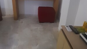 A room with a wooden bench, a red cushion, and a desk with a computer and keyboard.