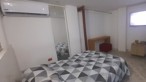 A bedroom with a bed, a TV, a mirror, and a wardrobe.