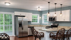 A spacious kitchen with a large island, bar stools, and a stainless steel refrigerator. - Poconos Getaway / Lake, Pools, Fire Pit & Ski Big Bear / Sleeps 10 (Lackawaxen)