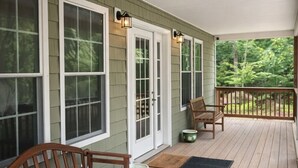 A covered porch with wooden flooring, two wooden benches, and a door with glass panels. - Poconos Getaway / Lake, Pools, Fire Pit & Ski Big Bear / Sleeps 10 (Lackawaxen)