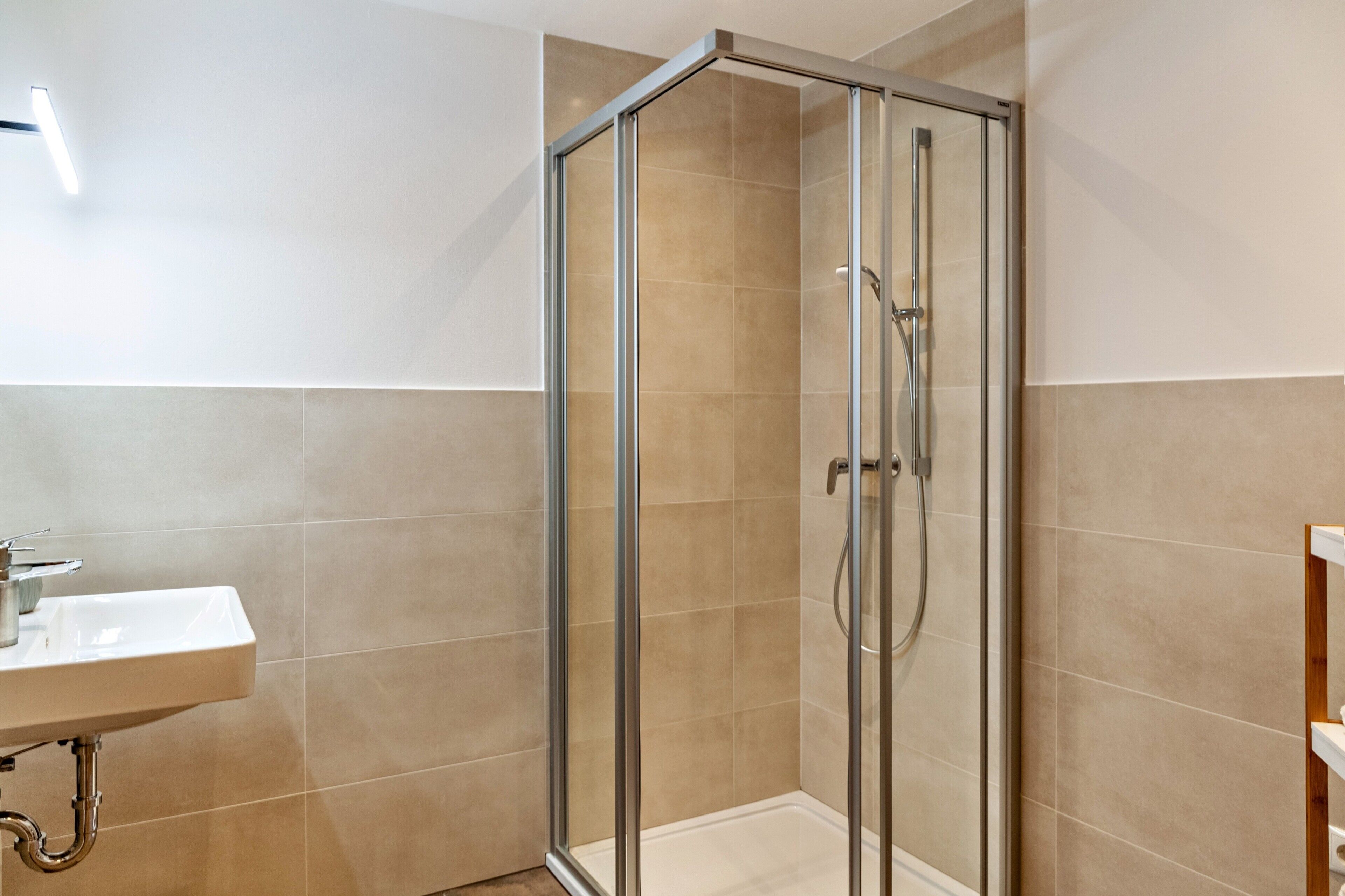 A bathroom with a glass shower enclosure, a sink, and a toilet.