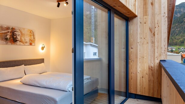 Un dormitorio con cama, una lámpara de pared y vistas a la montaña.