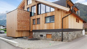 Una casa moderna de madera con base de piedra, ventanas grandes y techo inclinado.