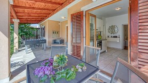 A covered patio area with a table and chairs, a foosball table, and a view of the house interior.