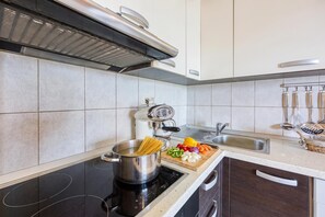 A modern kitchen with a stovetop, a sink, and a cutting board with vegetables.