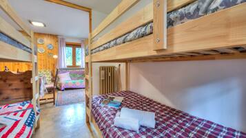 Une chambre avec un lit superposé, un plancher en bois, une petite table et une chaise.