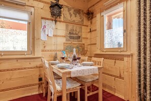 A wooden cabin interior with a dining table set for four, wooden walls, a world map, and a clock. - Nativa Log Cabin with Sauna, Podčetrtek, Slovenia (Podčetrtek)