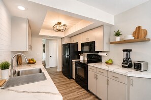 Una cocina moderna con un lavamanos de acero inoxidable, un refrigerador negro y un horno empotrado.