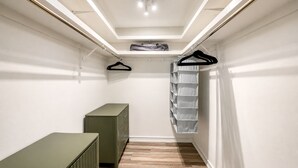 A narrow walk-in closet with a wooden floor, a green dresser, and a hanging storage unit. - Welcome to your dream oasis near the stunning Siesta Key!  (Sarasota)