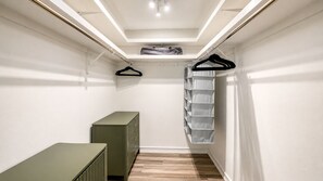 A narrow walk-in closet with a wooden floor, a green dresser, and a hanging storage unit. - Welcome to your dream oasis near the stunning Siesta Key!  (Sarasota)