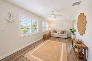 A spacious room with a large window, a ceiling fan, a white sofa, and a woven rug. - Welcome to your dream oasis near the stunning Siesta Key! (Sarasota)