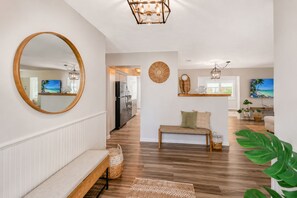 Un intérieur moderne avec un banc en bois, un miroir rond et un coin repas offrant une vue agréable.