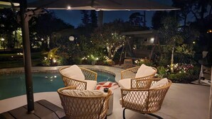 A poolside area with wicker chairs and a pergola. - Welcome to your dream oasis near the stunning Siesta Key!  (Sarasota)