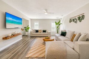 Una sala de estar moderna con sofá, mesa de centro y televisor de pantalla plana.