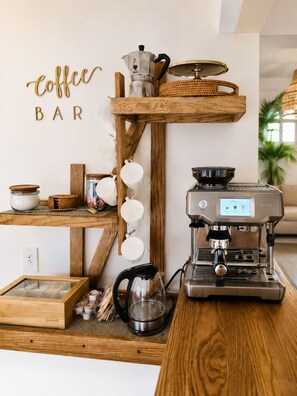 A coffee bar setup with a coffee machine, cups, and a sign that reads 'coffee bar'.