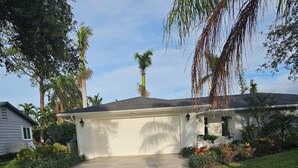 A residential driveway with a stone pavement leading to a garage, surrounded by lush greenery and palm trees. - Welcome to your dream oasis near the stunning Siesta Key!  (Sarasota)