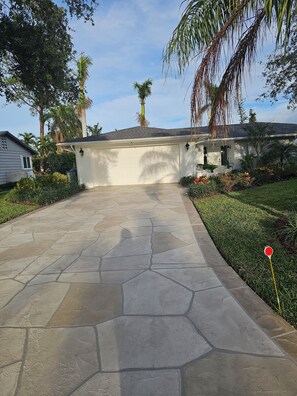 A residential driveway with a stone pavement leading to a garage, surrounded by lush greenery and palm trees. - Welcome to your dream oasis near the stunning Siesta Key!  (Sarasota)