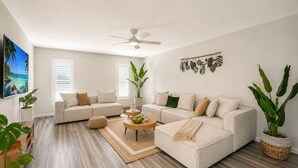 A modern living room with a sectional sofa, a coffee table, and large windows. - Welcome to your dream oasis near the stunning Siesta Key!  (Sarasota)