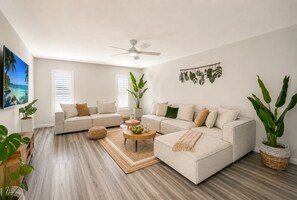 A modern living room with a sectional sofa, a coffee table, and large windows. - Welcome to your dream oasis near the stunning Siesta Key!  (Sarasota)