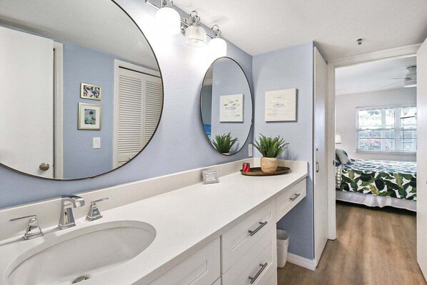 A bathroom with a large mirror, a sink, and a potted plant. - Charming Siesta Key condo with beach access - GBB 1204 (Siesta Key)