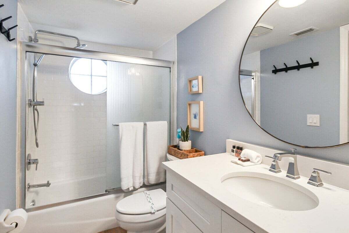 A modern bathroom with a glass-enclosed shower, a white toilet, a large sink with a mirror, and a towel rack.
