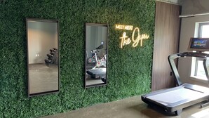 Un gimnasio con pared verde, una cinta de correr y dos espejos.