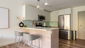 Una cocina moderna con una isla central, taburetes de bar, electrodomésticos de acero inoxidable y un diseño minimalista.