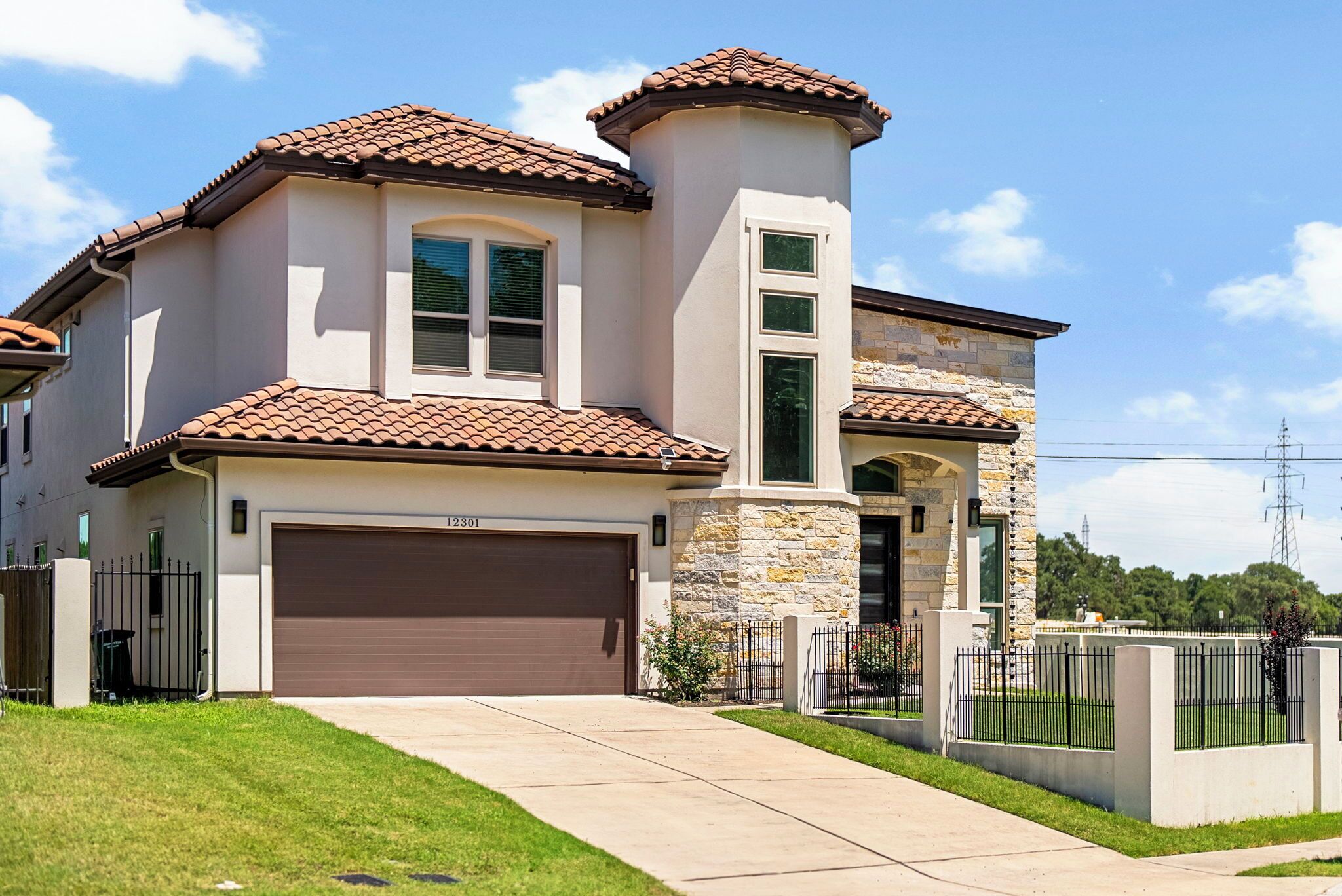 A two-story house with a brown garage door, stone accents, and a well-maintained lawn.