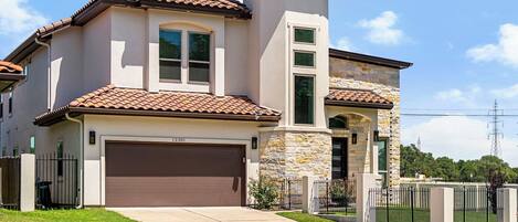 A two-story house with a brown garage door, stone accents, and a well-maintained lawn.