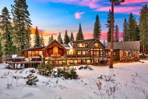 A lodge with multiple wooden buildings, a deck, and a snowy landscape.