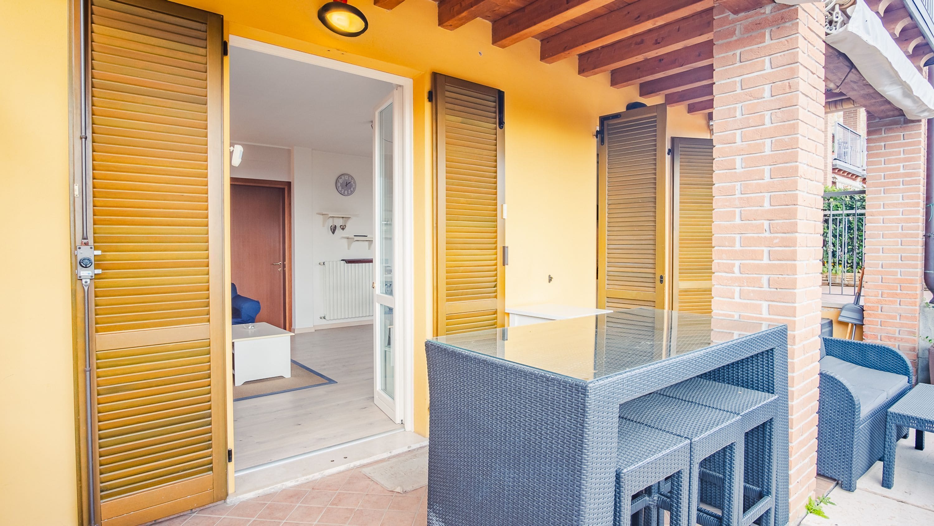 A room with a glass-top table, wicker furniture, and sliding doors.