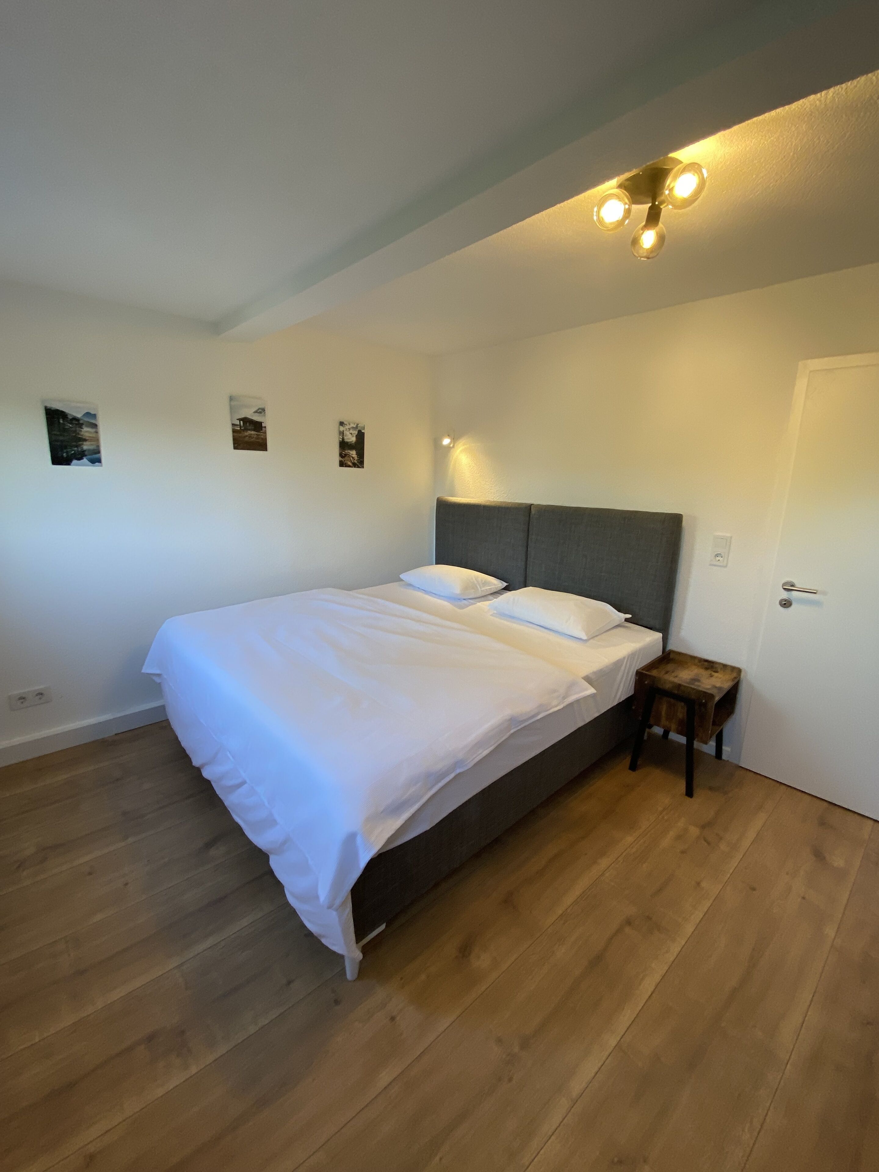 A bedroom with a bed, a nightstand, and a door.