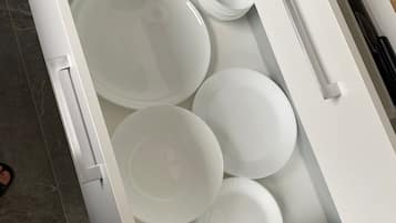 A kitchen drawer with white plates and bowls.