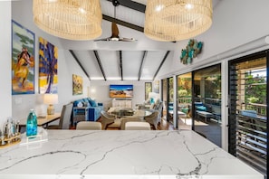 Uma sala de jantar moderna com mesa de mármore, cadeiras de vime e ventoinha no teto.